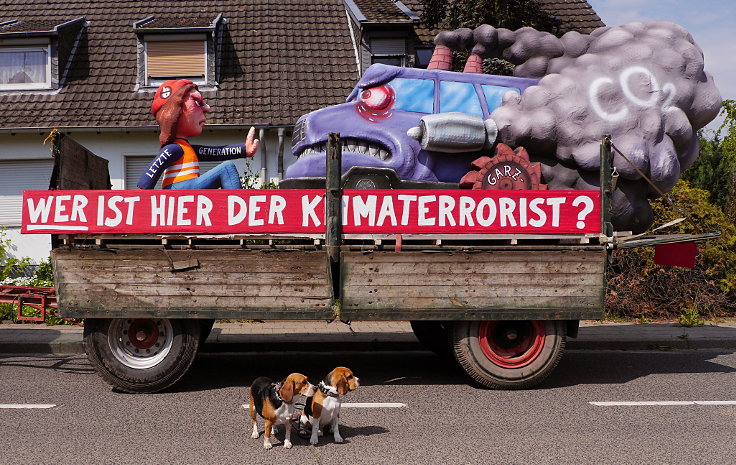Auf der Straße sitzende Hunde vor dem Karnevalswagen von Jacques Tilly 'WER IST HIER DER KLIMATERRORIST?' (2023)