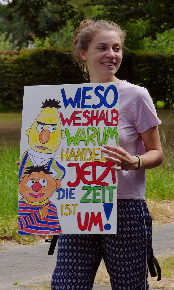 Schild: 'WIESO WESHALB WARUM – HANDELT JETZT DIE ZEIT IST UM!'